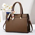 Détail du sac à main en cuir marron foncé avec foulard en soie et finitions dorées - Café