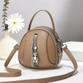 Dettaglio borsa tonda in pelle marrone con ciondolo a orso, nappa e scomparti con zip - 17x8x18 / Cachi