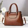 Detail of stone embossed pattern on brown faux leather handbag with gold hardware - Earthy Yellow