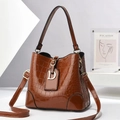 Detailed view of brown crocodile texture bucket bag with gold D-charm and shoulder strap - Earthy Yellow
