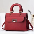 Detalle de bolso rojo con textura de lichi, hebilla metálica dorada y asa superior - Granate