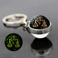 Detailed macro view of Libra constellation glass ball keychain with luminous glow effect - Libra