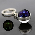 Macro shot of Libra constellation luminous glass ball keychain with blue and green glow - Libra