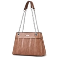 Macro detail of brown leather bag showing premium vertical ripple texture and metal chain strap - Pink