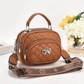 Detail of brown quilted crossbody bag featuring a metal bow and floral patterned strap - 20x10x16cm / Earthy Yellow