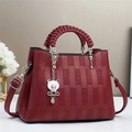 Detail of burgundy leather handbag with textured panels and cute metal bear charm - Red