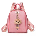 Detail eines rosa gestreiften Rucksacks mit Plüschbären-Anhänger und Goldreißverschlüssen - Rosa