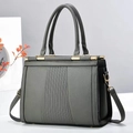 Macro detail of gray litchi textured leather on a tote bag with gold metal hardware - Gray