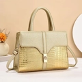 Detail of champagne gold handbag showing crocodile pattern texture and gold metal lock - Gold