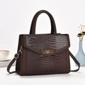 Macro detail of dark brown crocodile embossed leather handbag with golden hardware - Coffee