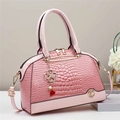 Dettaglio borsa a mano rosa motivo coccodrillo con hardware dorato e ciondolo a quadrifoglio - Rosa