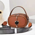 Detail of caramel leather bag featuring a cat-shaped pendant and striped woven strap - Earthy Yellow