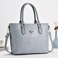 Detail einer hellblauen Patchwork-Ledertasche mit goldenem Logo und Schultergurt - Blau