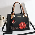 Elegant black leather handbag with red floral embroidery and silk scarf handle detail - Black