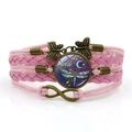 Detalle de una pulsera rosa multicapa de cuero con libélula de bronce y amuletos - Rosa