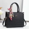 Elegante borsa nera con stampa coccodrillo, foulard di seta e logo dorato sulla scrivania - Nero