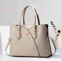 Close-up of stone pattern embossed texture and V-shaped stitching on beige tote bag - Off White