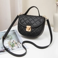 Black quilted shell shoulder bag with golden lock and detachable strap on a white surface - Black