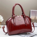 Detail of vintage burgundy leather handbag with gold rivets and metallic accents - Red