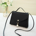 Black woven straw phone bag with gold clasp and pearl charm on white background - Black