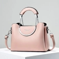 Detail of pink pebbled leather bag featuring circular silver metal handles and gold logo - Pink