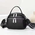 Black pebbled leather round bag with dual zippers and geometric woven shoulder strap - Black