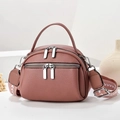 Detail of dusty rose leather bag featuring multi-layer zippers and woven strap - Pink