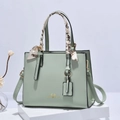 Minzgrüne Lederhandtasche mit dekorativem Seidenschal und Goldaufschrift auf weißem Stand - Dunkelgrün