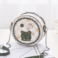 Mini round crossbody bag with green cartoon bear and chain strap shown in a lifestyle setting - Green