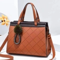 Detail of quilted leather tote bag with brown handles and a green pompom charm - L28 H22 W15 / Earthy Yellow