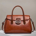 Close-up of brown faux leather tote bag featuring a metallic V-logo and retro texture - Earthy Yellow