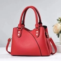 Close-up of red lychee textured leather tote with silver rivets and stitching detail - Burgundy