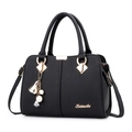 Bolso de mano negro con textura de lichi, detalles dorados y colgante decorativo - Negro