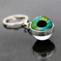 Macro shot of evil eye glass keychain with blue-yellow iris on black reflective surface - Triple Color Gradient Eye (JY007784-6)