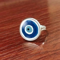 Macro side view of silver adjustable evil eye ring with blue glass charm on wood - Minimalist Blue White Eye (JY007909-12)