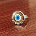 Detailed top view of silver Evil Eye ring with blue glass dome on wood surface - Blue White Gold Vortex (JY007909-10)