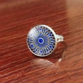 Detailed top view of an adjustable Evil Eye ring with blue mandala glass on a wood surface - Mandala Blue Gold (JY007909-7)