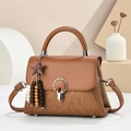 Detail of caramel leather handbag featuring stripe texture and silver metal buckle closure - Earthy Yellow