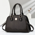 Detail of dark brown shell bag with herringbone fabric and golden logo emblem - Coffee