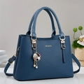Dettaglio borsa blu scuro in pelle martellata con logo dorato e ciondolo a perla - Blu
