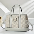 Detail of herringbone weave fabric and golden metal logo on a luxury shoulder bag - Gray