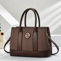 Detail of herringbone pattern tote bag with golden circular logo and dual top handles - Brown