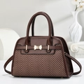 Close-up of brown herringbone woven handbag with golden bow metal buckle detail - Brown