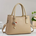 Elegante beige Tragetasche aus genarbtem Leder mit goldenem Logo und Anhängern - Khaki