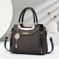Detail of elegant two-tone handbag with gold hardware, metal pendant, and chain strap - Coffee