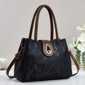 Elegante bolso tote negro jaspeado con asas marrones y herrajes dorados sobre fondo blanco - Negro