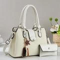 Detail view of a cream leather handbag set featuring an M buckle and a decorative charm - 2-Piece Set (Handbag + Wallet) / Off White
