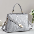 Détail d'un sac à main argenté avec texture métallique brossée et fermoir doré chic - Argent