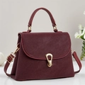 Detail of burgundy textured leather handbag featuring gold metal clasp and top handle - Burgundy