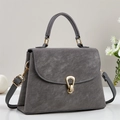 Close-up of retro matte grey handbag featuring a golden horseshoe swivel lock and top handle - Gray